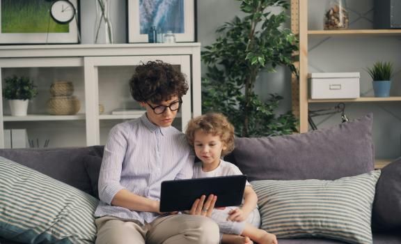 Een vrouw zit op een bank met een kind op haar schoot.
